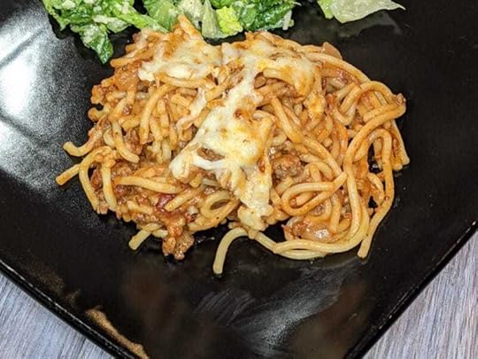 Baked Spaghetti on a plate with caesar salad