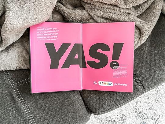 A photo of The Queens English, open to the inside cover with the giant word YAS on a bright pink background.