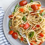 Close up of a plate of tomato basil pasta with a blue and white kitchen towel