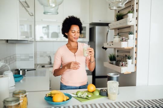 woman making and drinking a fresh green smoothie