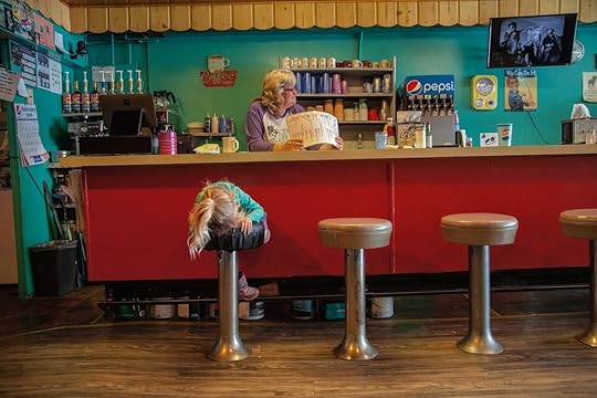 a young girl on the bar stool of a diner