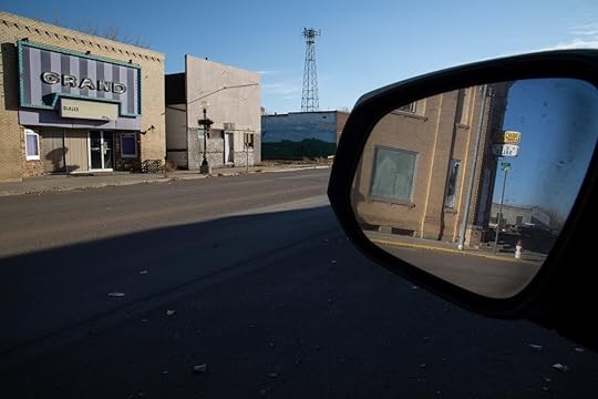 a rearview mirror along a road of empty buildings