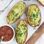 Three potato skins stuffed with guacamole with a small bowl on the side filled with salsa
