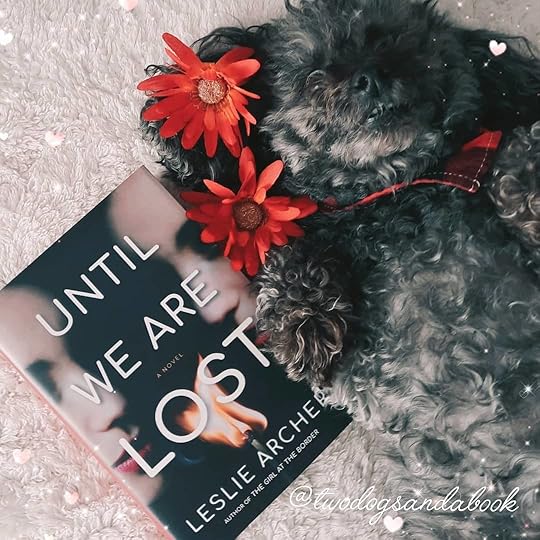 Cute dog with a copy of the book entitled Until We Are Lost by Leslie Archer