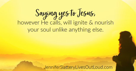 Woman standing on a mountain top gazing out over sunlit cloud cover