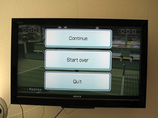 Image: television displaying a video game menu of three buttons labeled Continue, Start Over, and Quit