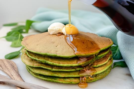 Stack of 4 green pancakes with a dollop of butter and maple syrup drizzling