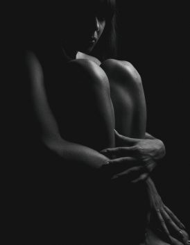 black and white image woman hugging bare knees