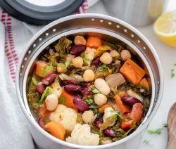 Insulated container filled with a hearty kale and bean soup