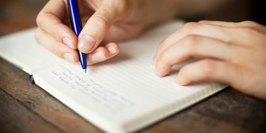 Image of hands writing with a pen in an open journal
