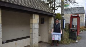 Photo of Debbie at bus stop with book box
