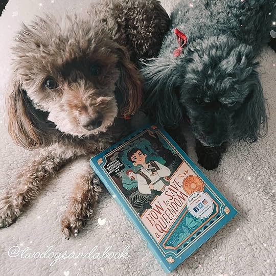 Two cute miniature poodles with a copy of the book entitled How to Save a Queendom by Jessica Lawson.