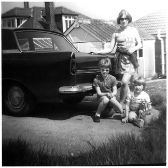 Black a white photo of a late 60s car parked in front of a holiday bungalow and three girls aged 14, 7, and 3