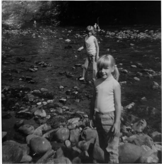 Black and white [photo of two girls standing in a river looking straight at the camera