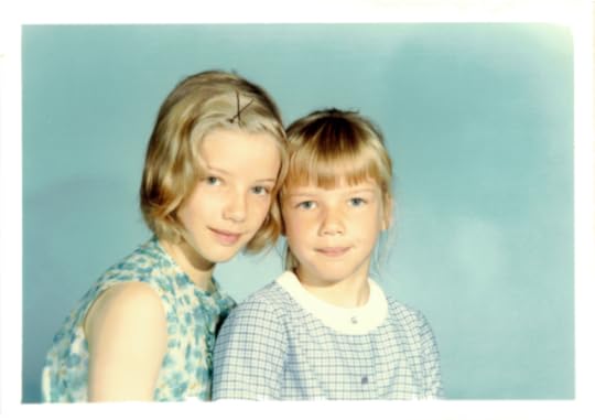 Colour photo of two sisters,both with blonde hair and blue eyes, against a professional hot background—aged 10 and aged 7
