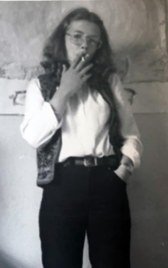black and white photo of a teenage girl in glasses smoking a cigarette and staring at the camera