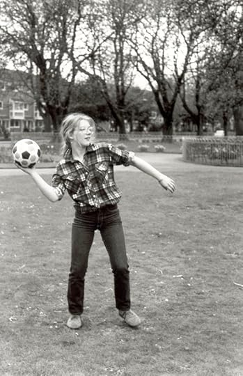 Black and white photo of a long haired teenaged girl in glasses about to throw a football
