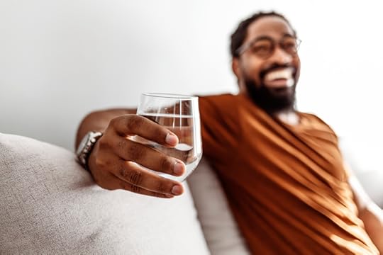 Cropped shot of a young man drinking a glass of water at home