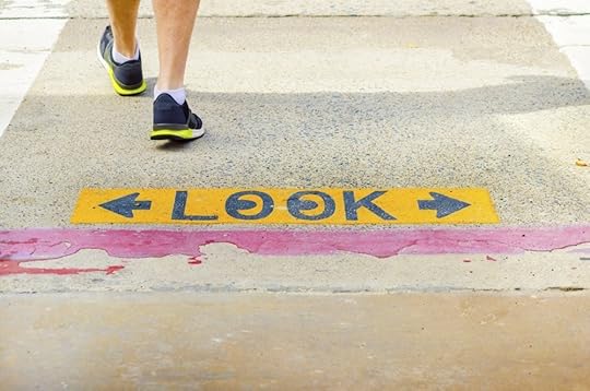 Image: person walking across pavement which is painted with signage indicating to look both ways