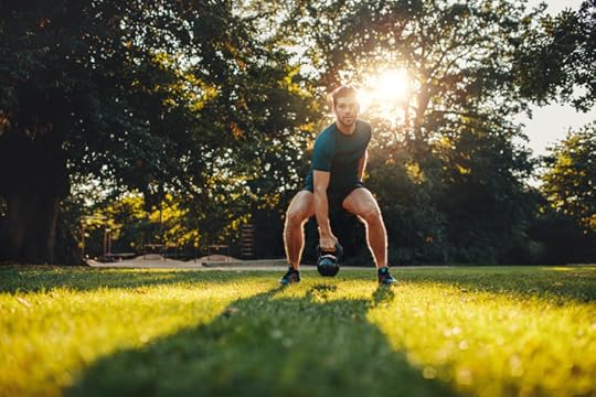 Full length portrait of fitness young man training with kettlebell in the park. Fit caucasian model doing physical workout in the park.