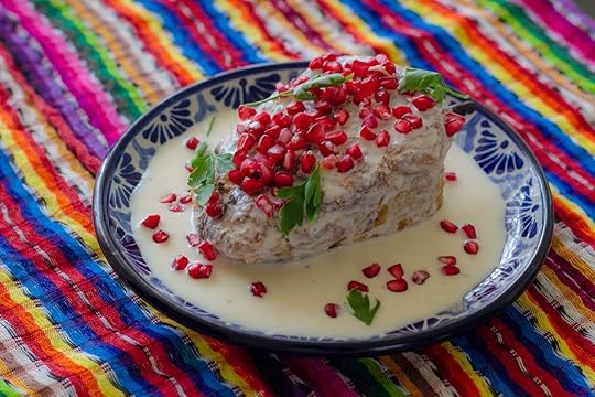 Chili in nogada in talavera design dish on colorful background, Puebla Mexico