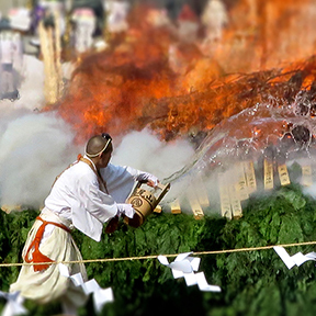 Monk throwing water on flames at Mt. Takao Hiwatari Matsuri