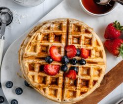 Two Waffles Stacked on top of each other with berries and syrup on top