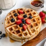 Two Waffles Stacked on top of each other with berries and syrup on top