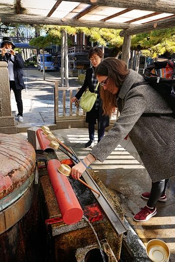 Western woman using the traditional hand washing basin at Shibamata temple, Japan
