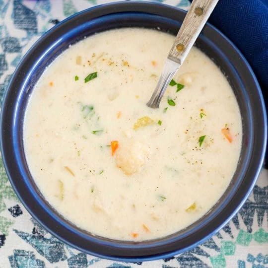 A blue bowl filled with crock pot cheesy cauliflower soup.