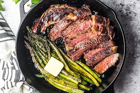 perfectly medium rare steak in a cast iron skillet with grilled asparagus