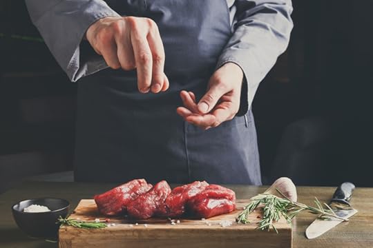 Chef seasoning filet mignon on wooden board at restaurant kitche