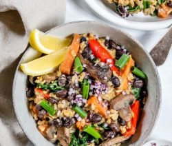 Two bowls of veggie filled rice pilaf with two wedges of lemon in the side