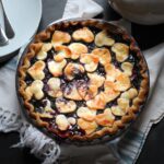 blueberry pie with a golden crust of hearts on white and blue towel.