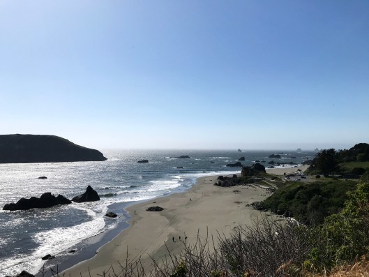 Oregon beach scene with blue sky, waves, sand and cliffs 