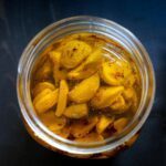 overhead view of the open jar of roasted garlic cloves in oil.