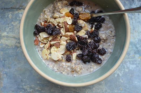 Prepared homemade instant oats in a pale green bowl, topped with raisins and sliced almonds.