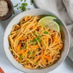 Bowl of Sesame Salad with Two Wedges of Lemon on a Grey Surface