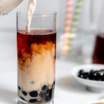 Tall Glass with Boba Tea and a Jug of Plant-Based Creamer Pouring into it