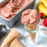 Cone with a scoop of strawberry banana ice cream inside a clear jar