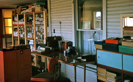 A makeshift office on an enclosed porch with a desk and cabinets and a typewriter and shelves full of sales stock. The value of family history can be appreciated when we learn about our family's past.