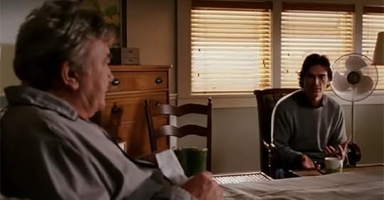 A scene from the movie Big Fish where father and son sit at at table in what might be tense conversation. This movie reveals the value of family history because it's not always easy to obtain those histories.