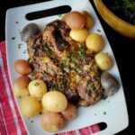 slow cooked chuck roast on platter with herbs and tri-color potatoes.