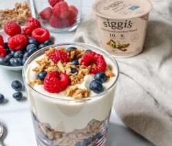Glass with vegan yogurt and granola with berries at the bottom