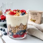 Glass with vegan yogurt and granola with berries at the bottom