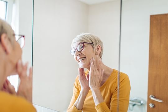 senior woman practicing face yoga in the mirror