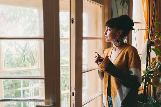 woman looking outside sipping a beverage