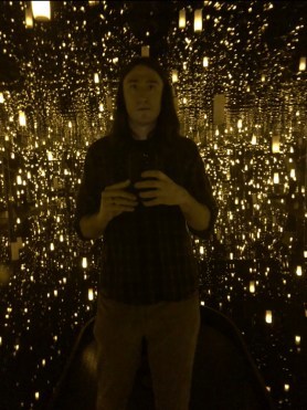 Daniel Bailey against a starry background at Kusama's Infinity Mirrors art exhibit.
