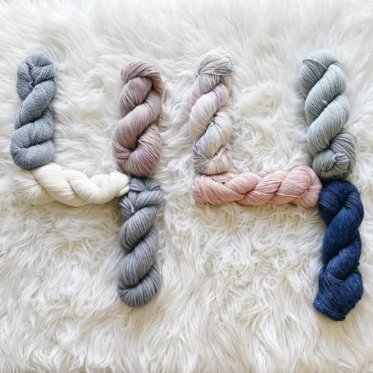 Close up of white shag rug with skeins of wool in shades of blues, creams and pinks laid out in the shape of the number 44