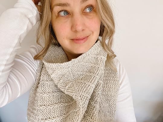 Close up of Shannon wearing a grey textured neck accessory and white shirt with arm up behind head.